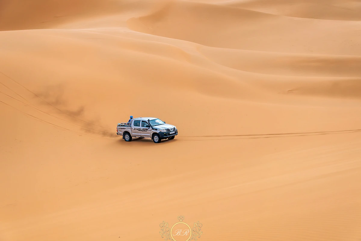Paysage désertique avec un 4x4 filant à l'horizon